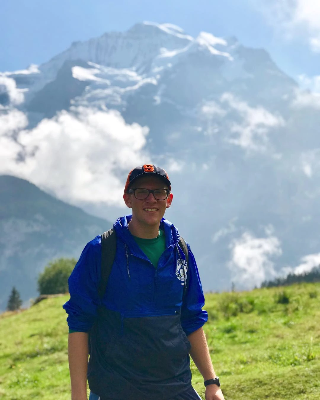 Jacob Bellotti outdoors in a blue windbreaker with mountains in the background