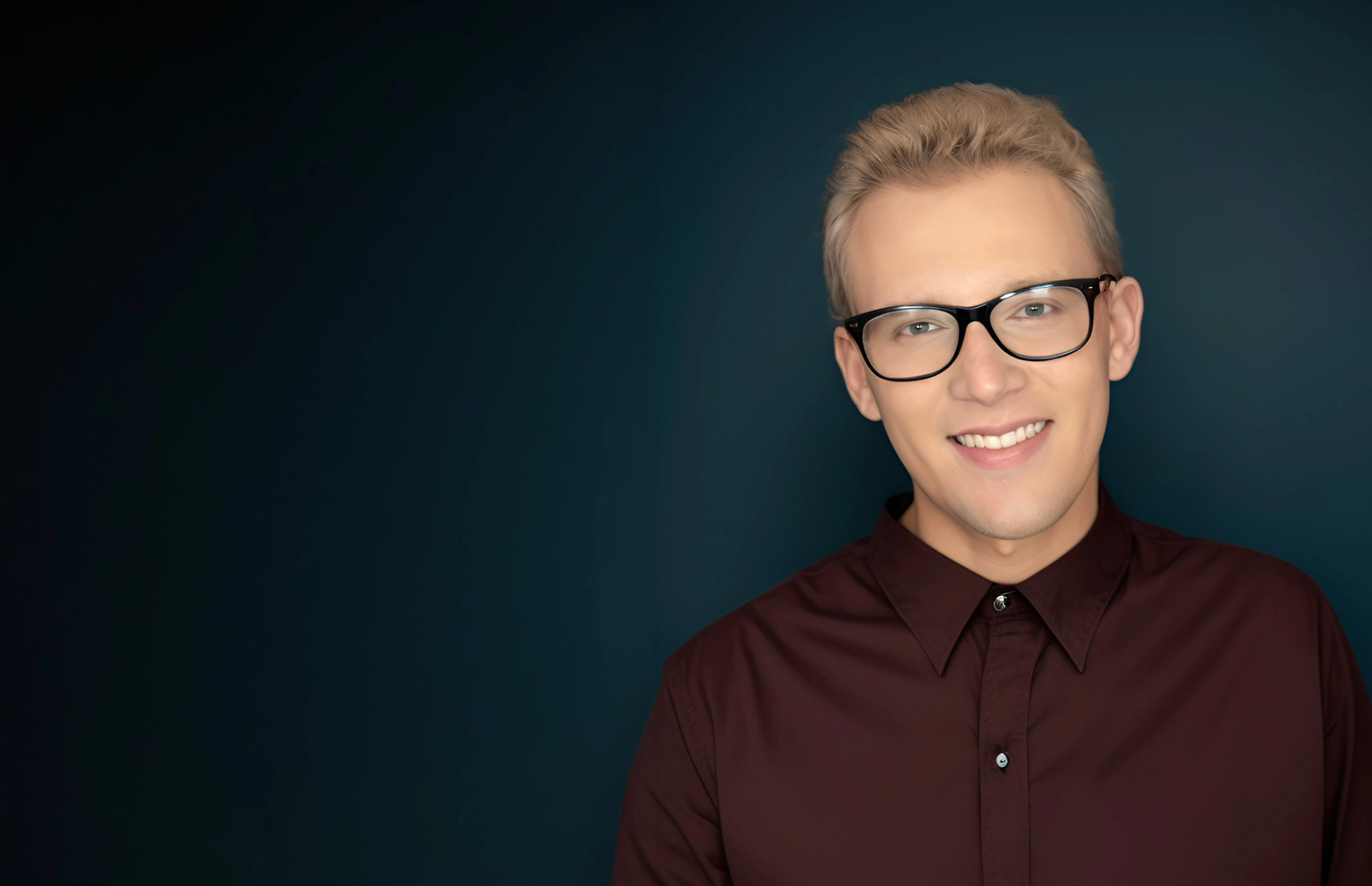 Jacob Bellotti smiling, wearing glasses and a burgundy shirt